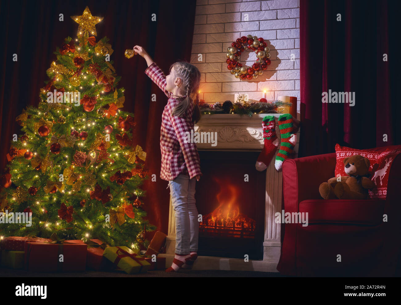 Joyeux Noël et de bonnes vacances ! Mignon petit enfant fille est la décoration de l'arbre de Noël à l'intérieur. Les traditions familiales de Noël. Banque D'Images