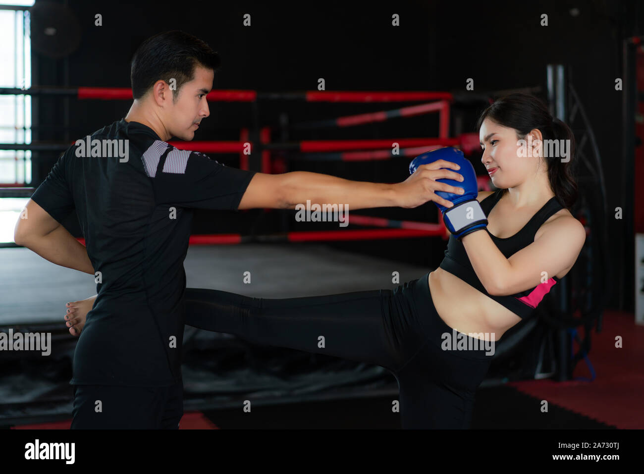 L'homme asiatique pratique formateur professionnel à coups de jeune femme boxer dans studuim boxe dans l'arrière-plan à la salle de sport de remise en forme. Mettre en place pour une lifest sportive Banque D'Images