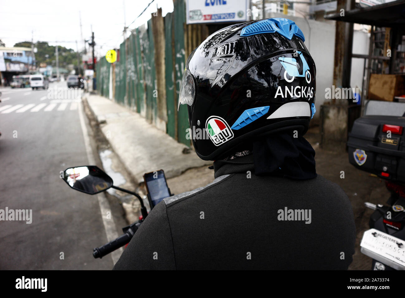 ANTIPOLO CITY, PHILIPPINES - 28 octobre 2019 : conducteur de moto taxi driver est populaire par le trottoir sur sa moto et attendre une passen Banque D'Images