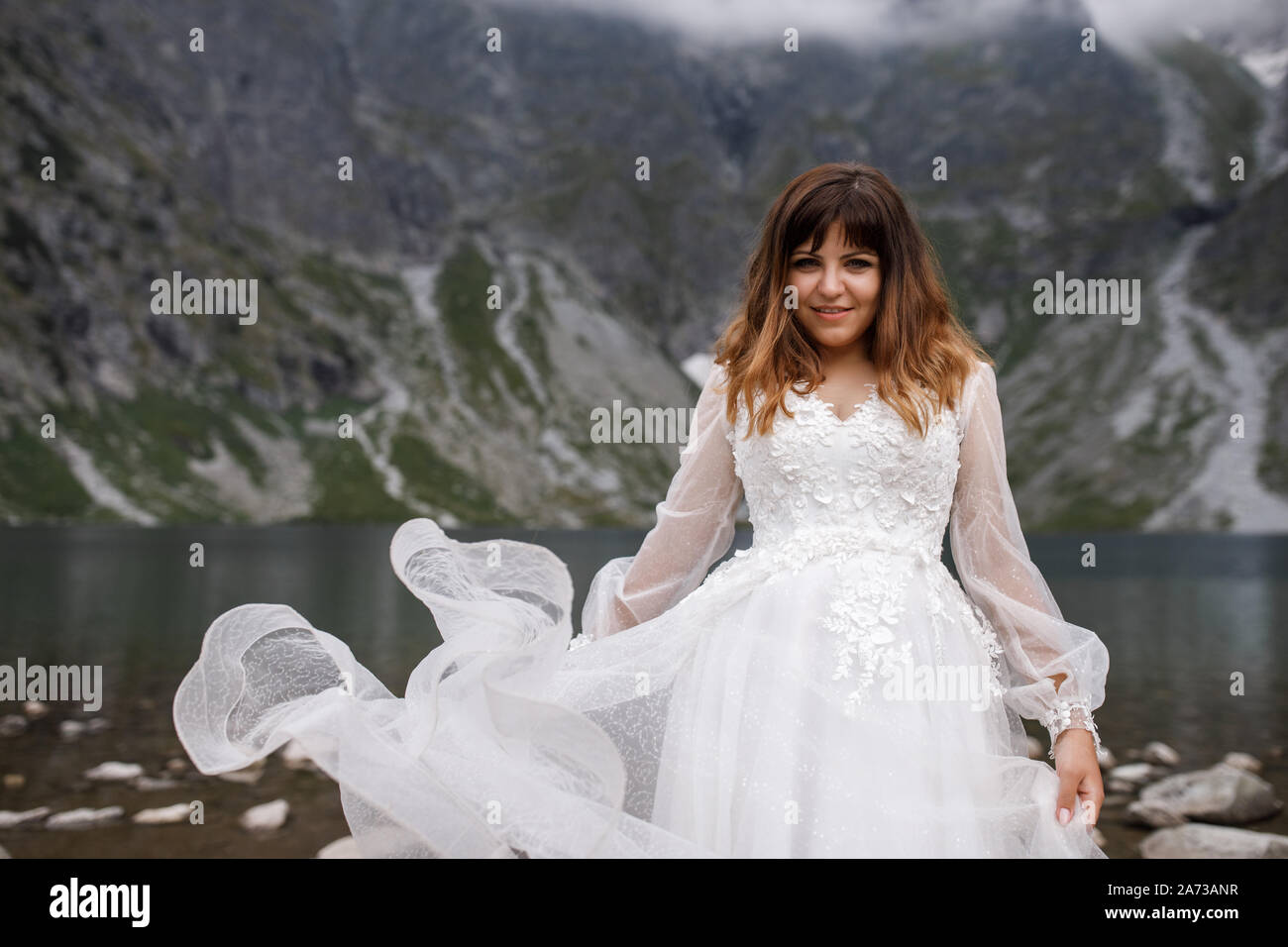 Jolie jeune femme passer du temps dans les montagnes près du lac. La mariée se présente. Banque D'Images