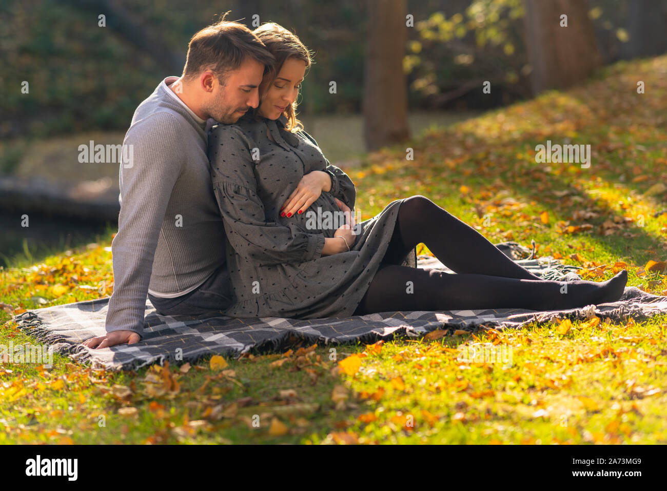 L'amour tendre couple avec femme enceinte détente sur une couverture dans le parc avec leur bébé à venir Banque D'Images