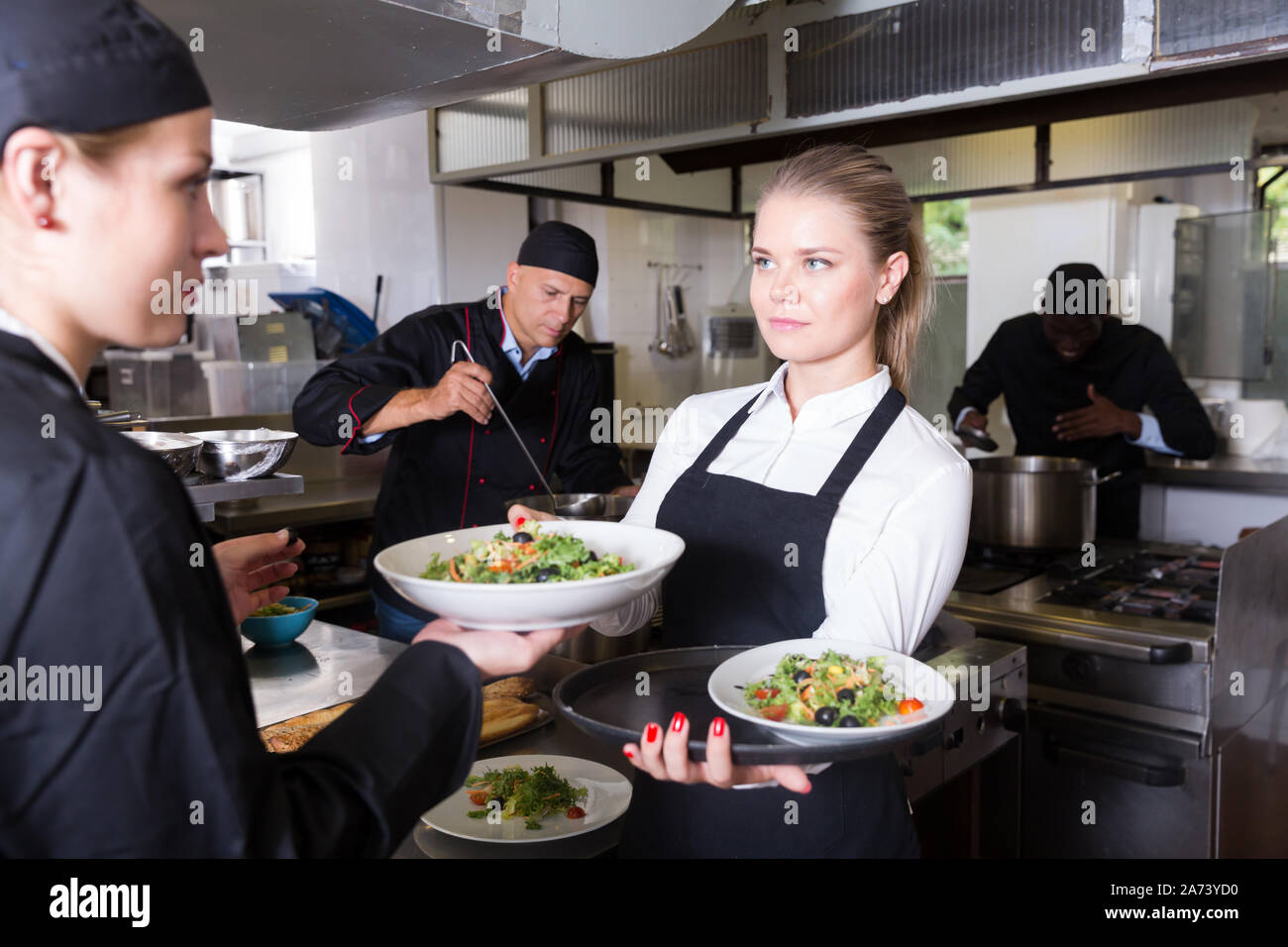 Young waitress préparé des plats du chef en cuisine de restaurant moderne Banque D'Images