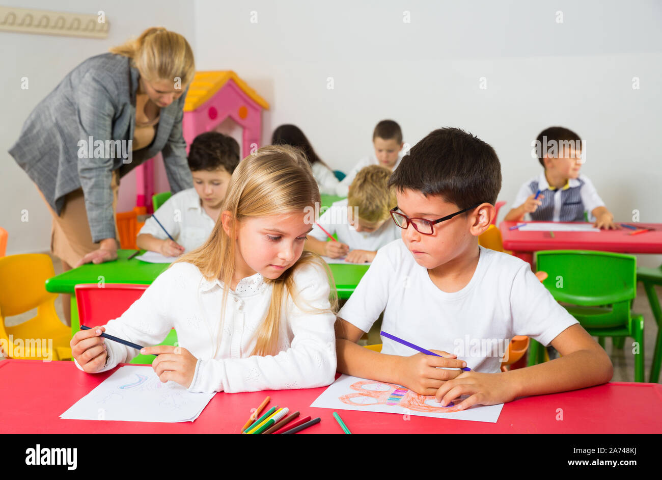 Les élèves heureux assis bavardant à leçon à l'école élémentaire Banque D'Images