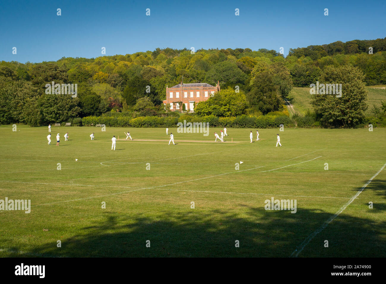 Un match de cricket de village à Hambleden, Buckinghamshire avec la maison Kenricks classée Grade II derrière, construite en 1725 Banque D'Images