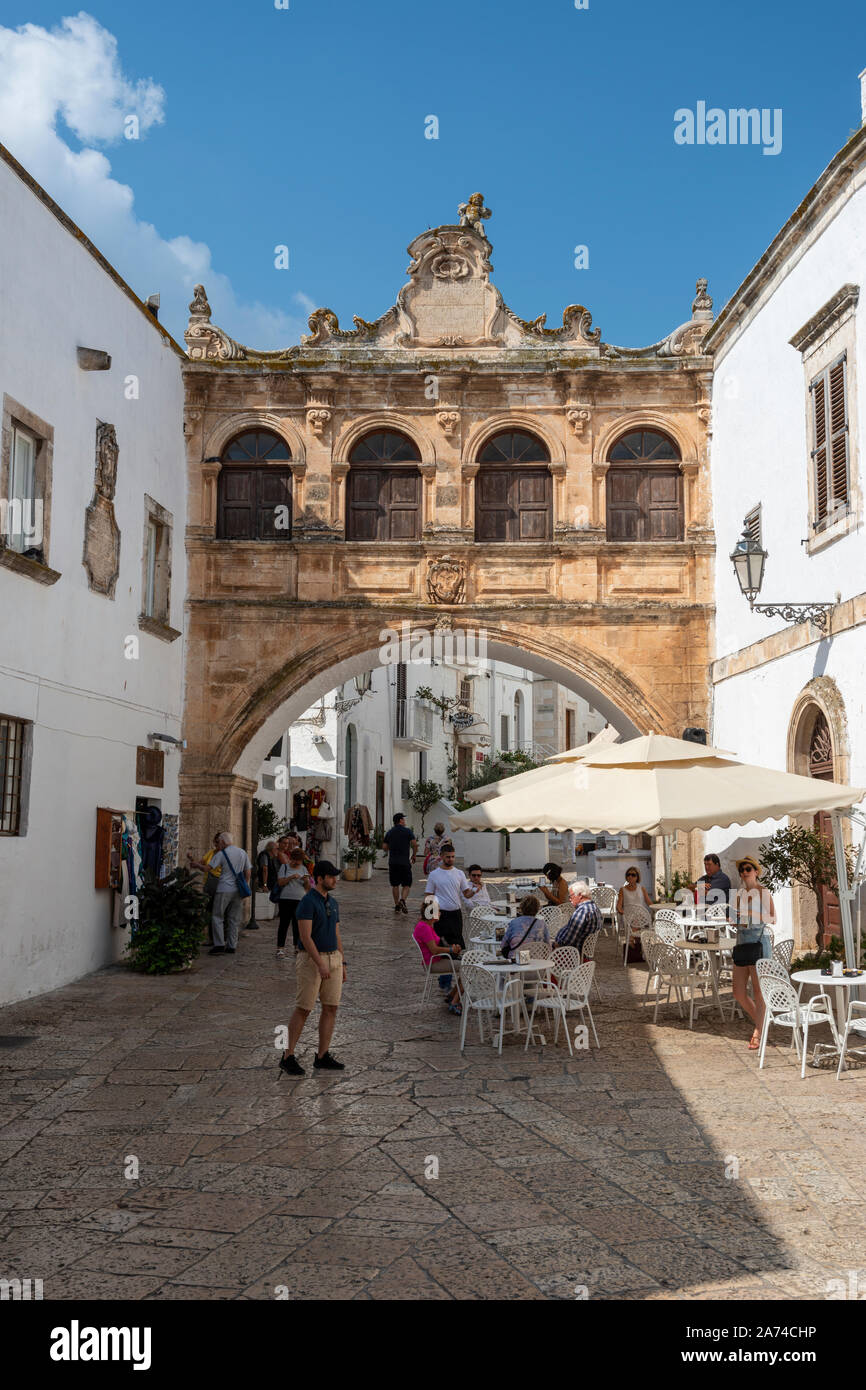 Café en plein air sur Largo Arcid Teodoro Trinchera avec Arco Scoppa (17e siècle arch) en arrière-plan - Ostuni Pouilles (Puglia), dans le sud de l'Italie Banque D'Images
