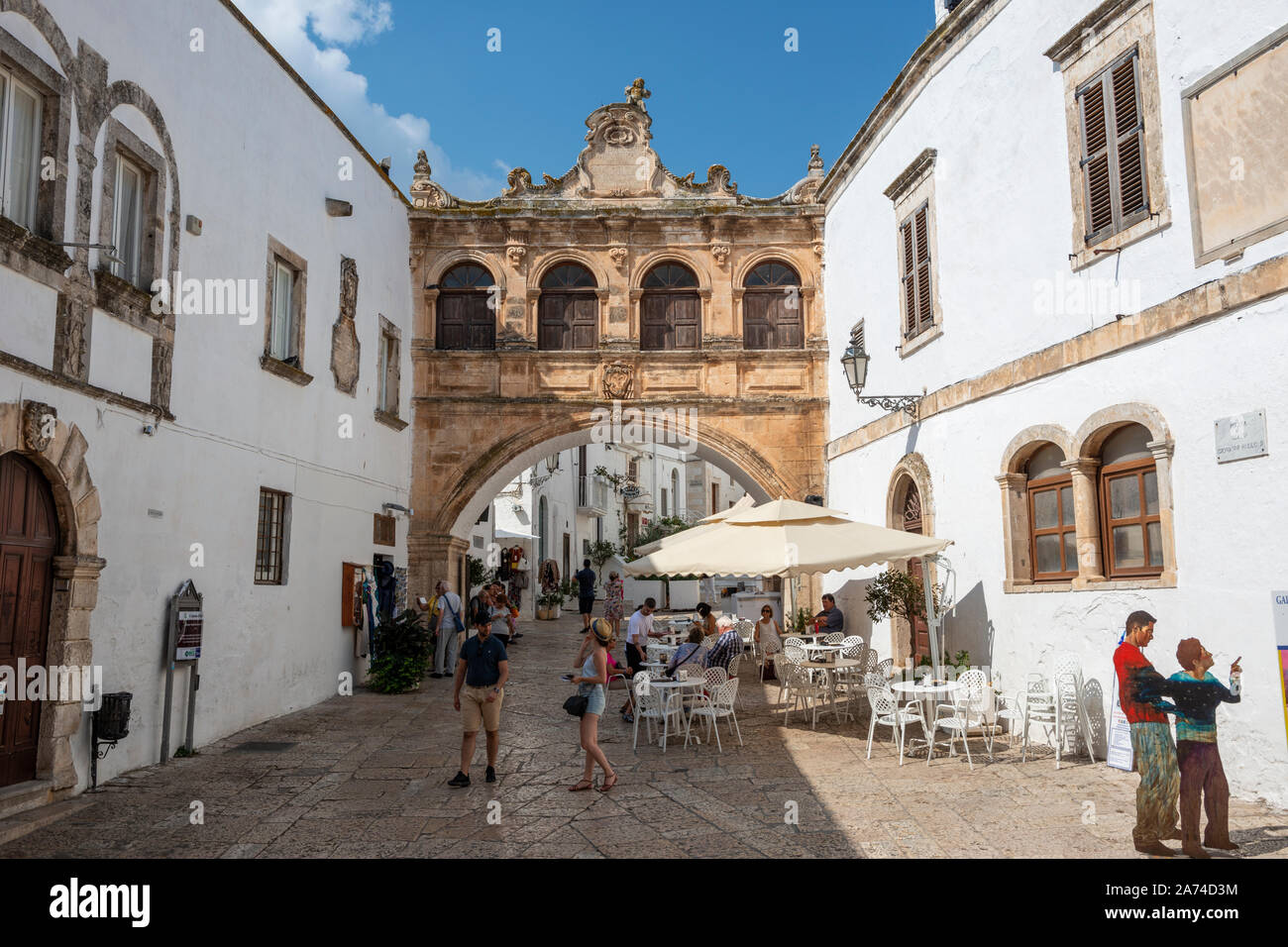 Café en plein air sur Largo Arcid Teodoro Trinchera avec Arco Scoppa (17e siècle arch) en arrière-plan - Ostuni Pouilles (Puglia), dans le sud de l'Italie Banque D'Images
