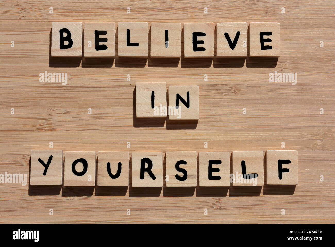 Croyez en vous-même. Mots de motivation en 3d wooden alphabet lettres sur un fond de bois de bambou Banque D'Images