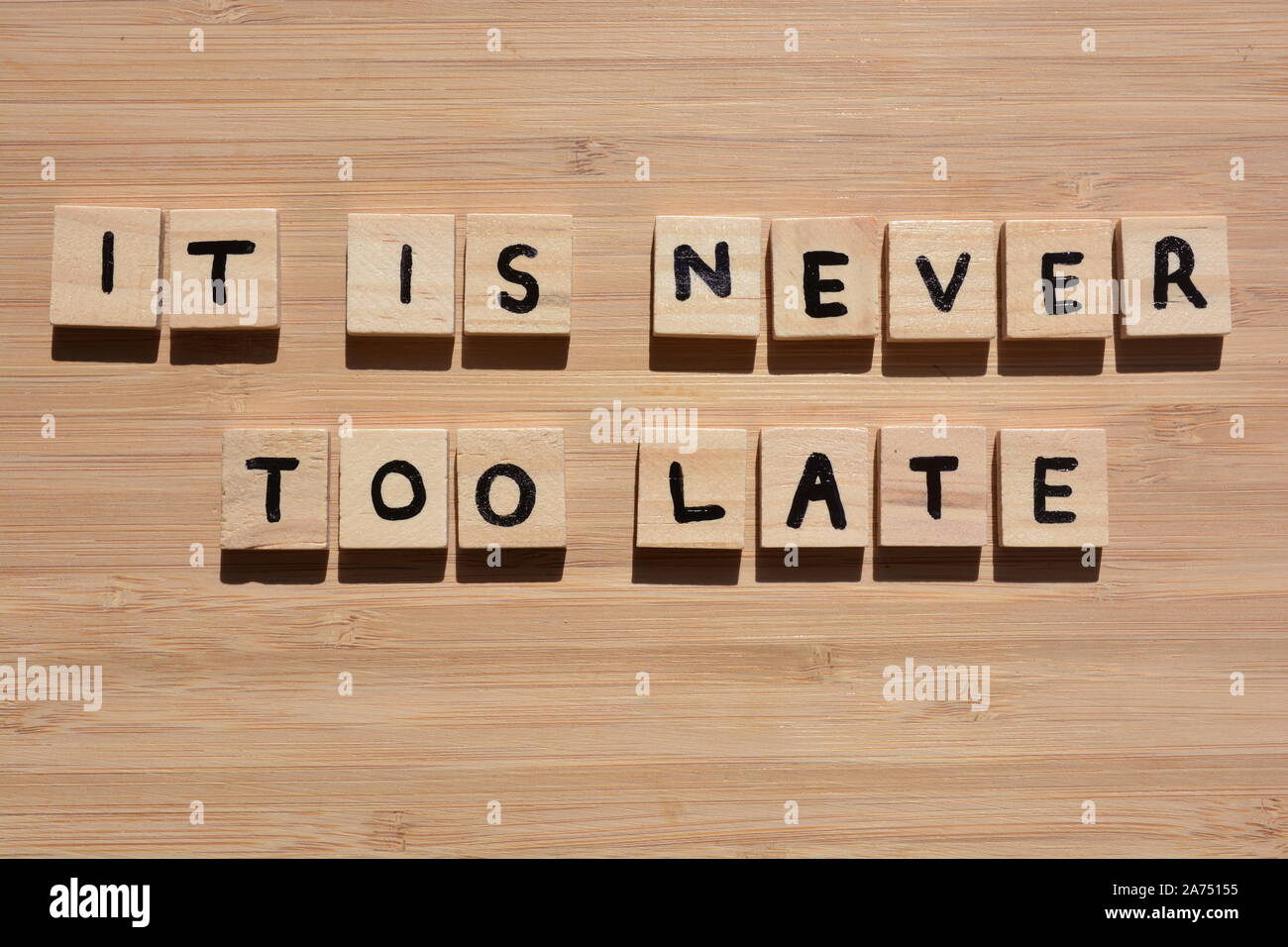 Il n'est jamais trop tard. Mots de motivation en 3d wooden alphabet lettres sur un fond de bois de bambou Banque D'Images