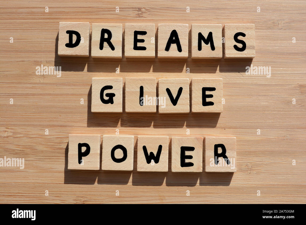 Les rêves donnent du pouvoir. Mots de motivation en 3d wooden alphabet lettres sur un fond de bois de bambou Banque D'Images