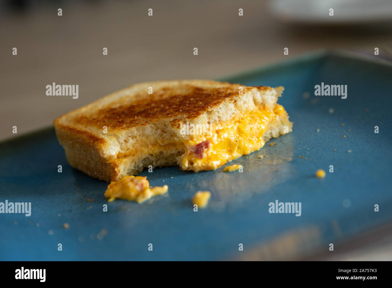 Vue latérale d'une moitié d'un piment grillé au fromage sur une plaque bleue avec un morceau manquant. Banque D'Images