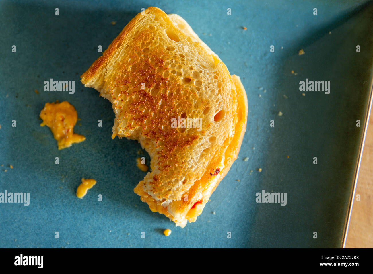 Vue de dessus de la moitié d'un piment grillé au fromage sur une plaque bleue avec deux morsures manquant. Banque D'Images