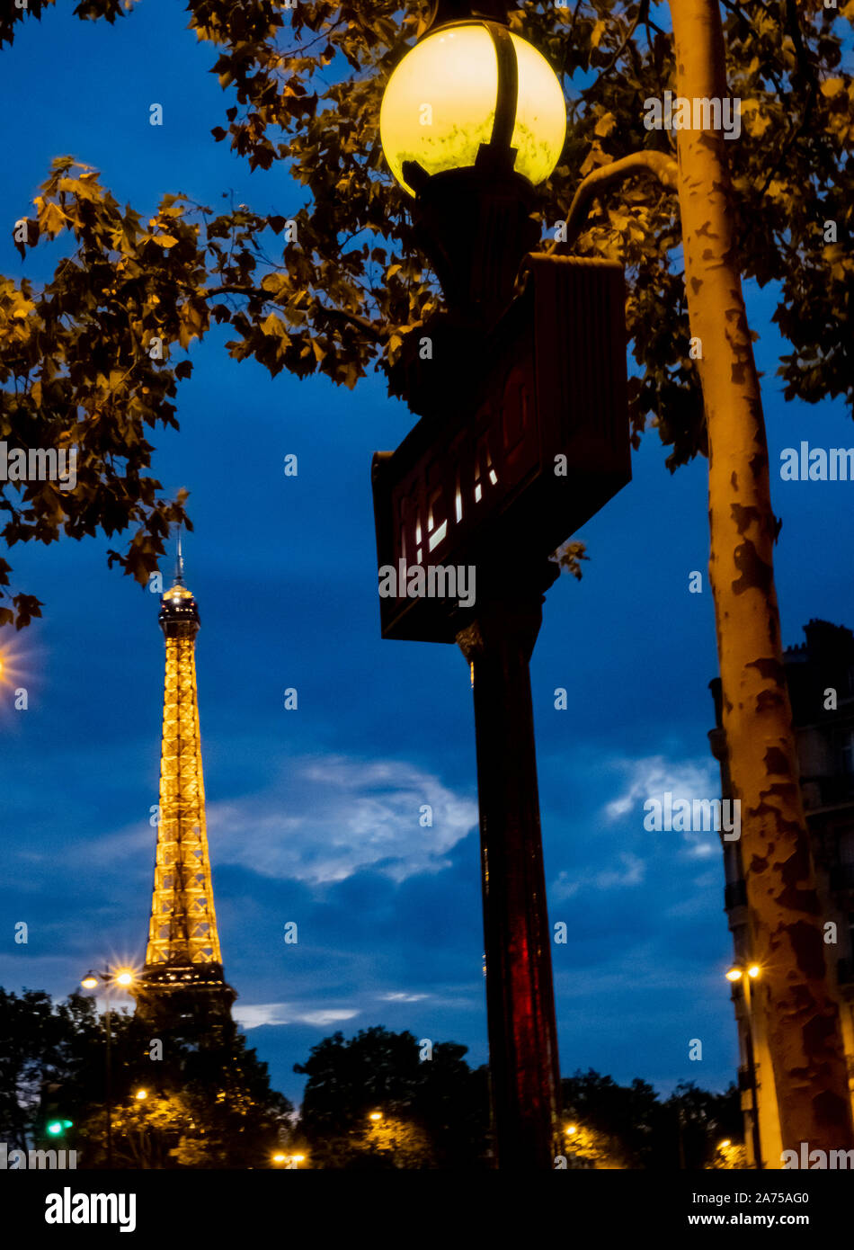 Un signe de métro art déco emblématique de l'autre côté de la Seine avec la Tour Eiffel en pleine lumière après le coucher du soleil Banque D'Images