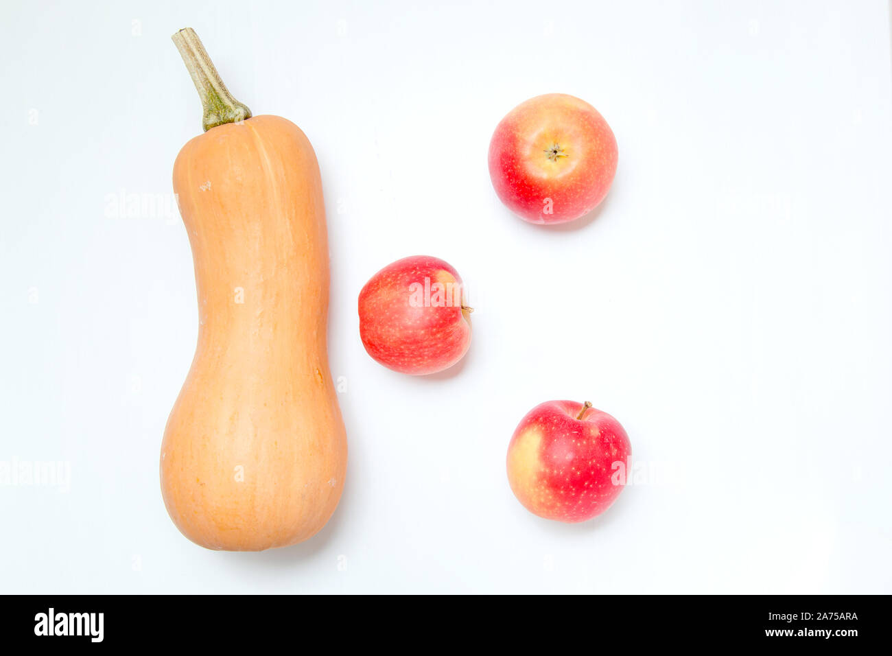 Une citrouille et trois pommes sur fond blanc. Ingrédients pour salade de régime ou du jus de fruits fraîchement pressés. Banque D'Images
