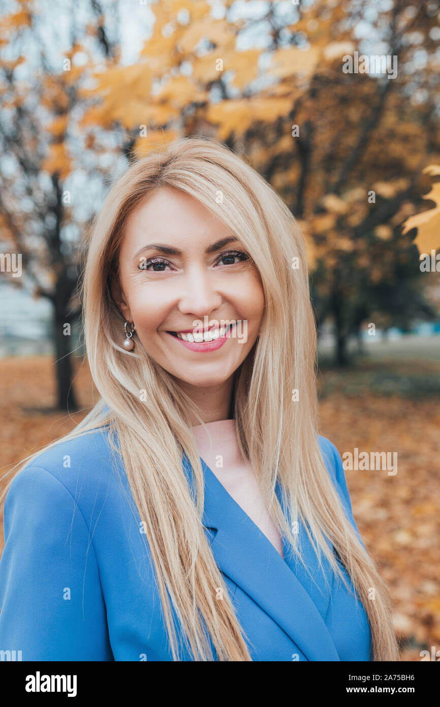 Close-up portrait of happy young blonde woman smiling à l'appareil photo. in autumn park Banque D'Images