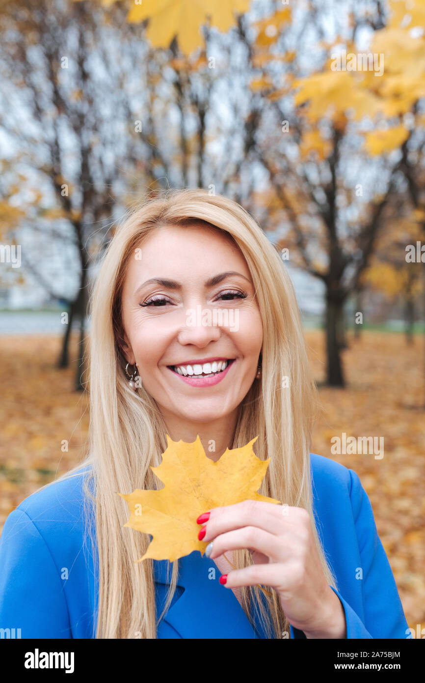 Portrait de belle blonde mature woman holding autumn leafs dans la nature. Banque D'Images