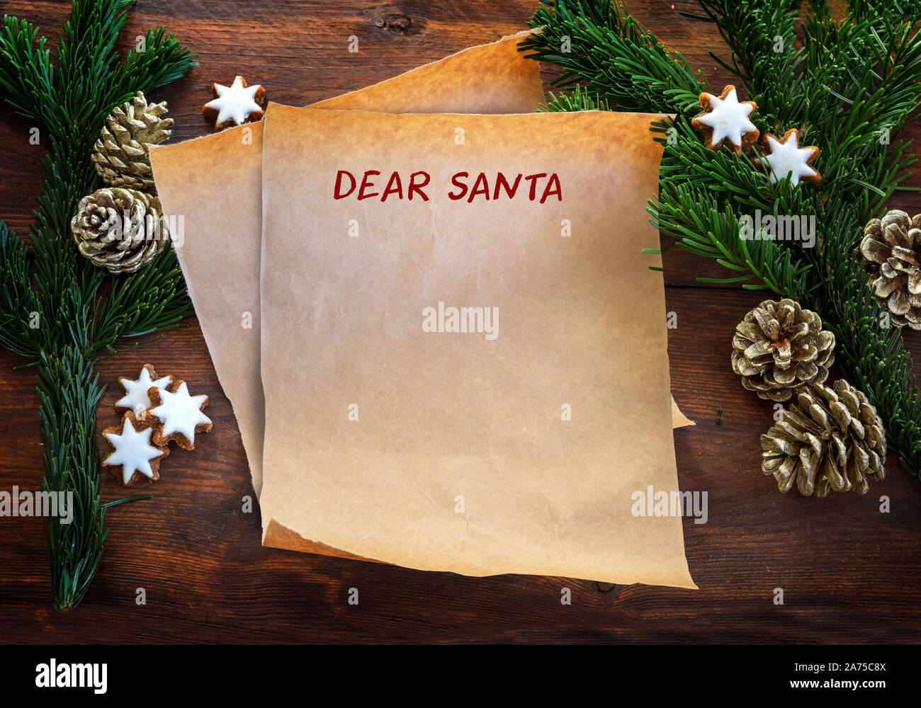 Feuille de papier avec texte Cher Père Noël, entre les branches de sapin, étoiles à la cannelle et des pommes de pin rustique en bois sombre, sur la liste de souhaits de Noël ou une lettre à Santa Clau Banque D'Images