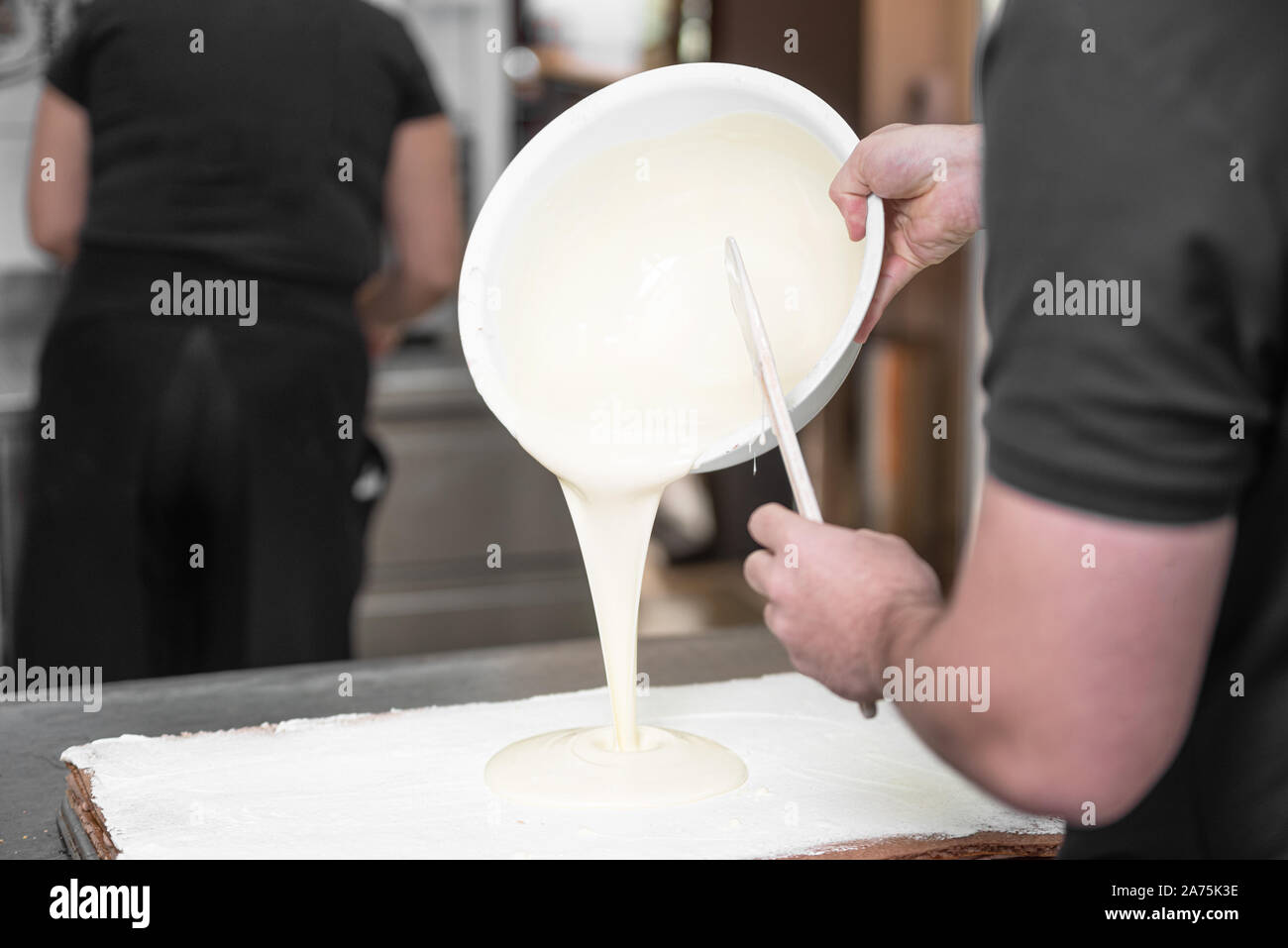 Verser la crème pâtissière chaude. Close up Portrait d'un pâtissier professionnel pour la préparation de desserts au remplissage cuisine étape par étape . Banque D'Images