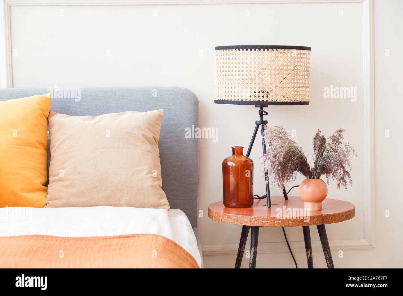 Lampe de chevet en bois élégant à côté de fleur en grand vase en verre à l'intérieur chambre à coucher scandinave Banque D'Images