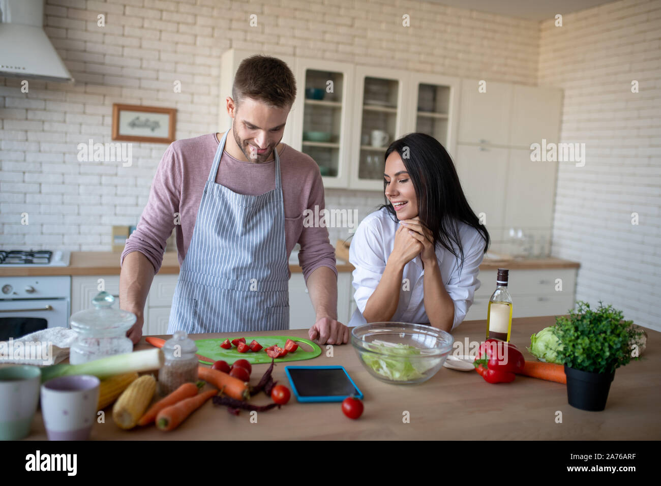 Femme regardant mari slicing tomatoes pour omelette Banque D'Images