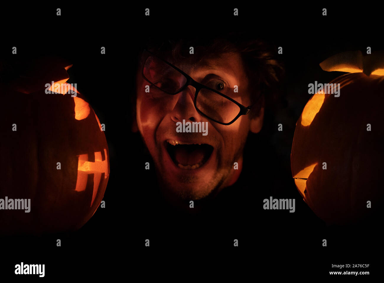 Effrayé l'Homme à lunettes entre deux citrouilles d'halloween. Concept d'Halloween Banque D'Images