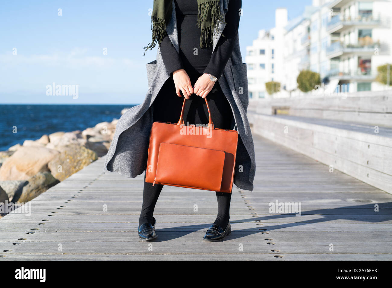 Personne debout sur promenade avec sac en cuir rouge Banque D'Images