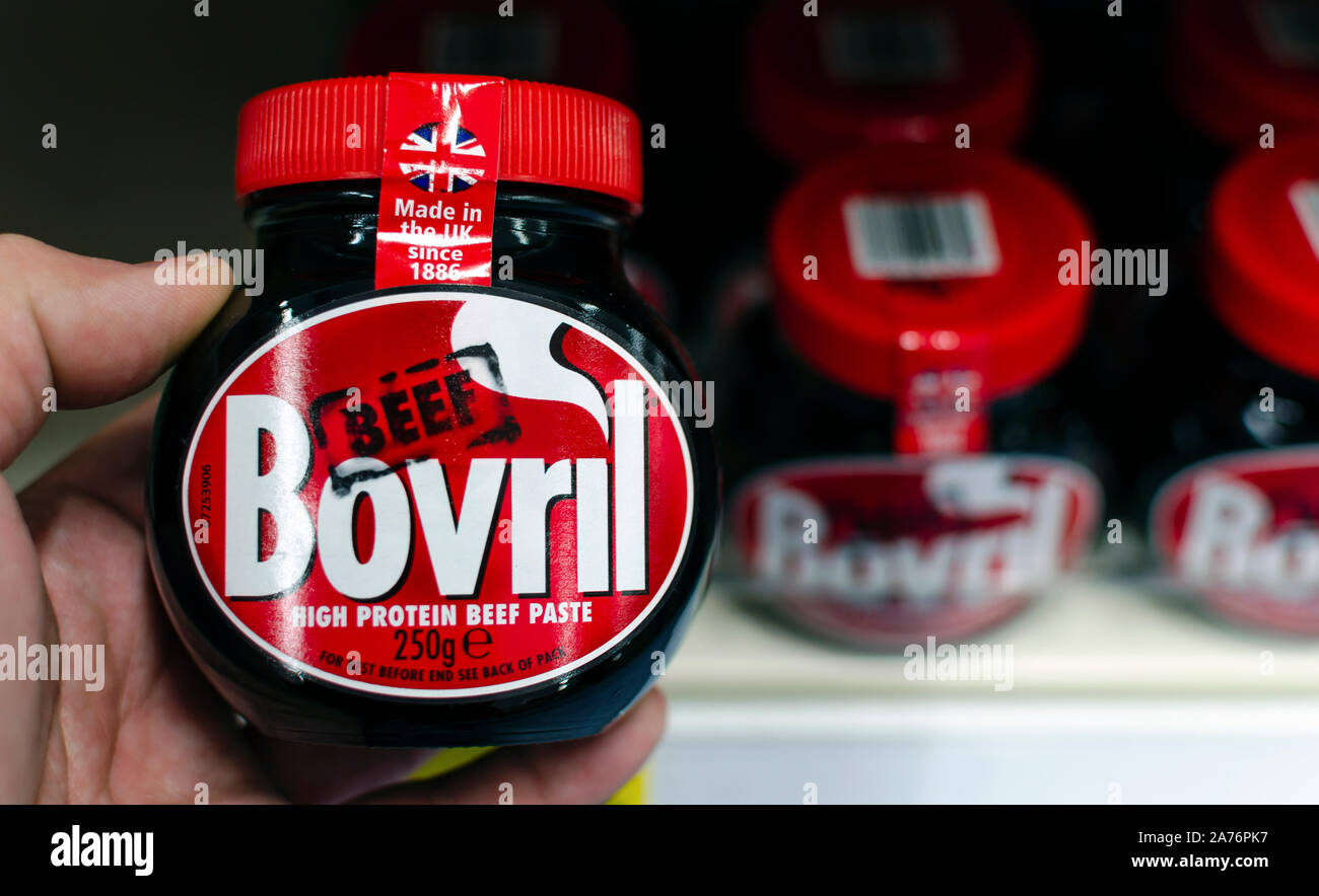 Jar Bovril dans une main tenir à côté d'autres pots sur l'étagère. Est un épais Bovril et extraits de viande salée. La viande bovine britannique original boisson chaude. Banque D'Images