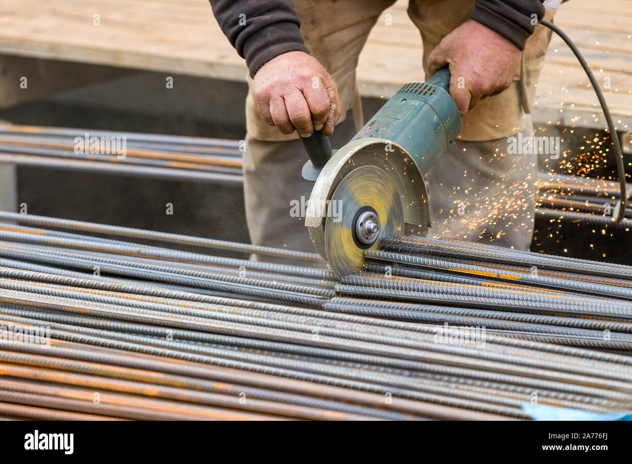 Les mains des hommes d'acier de coupe circulaire bars avec une meule électrique. Banque D'Images