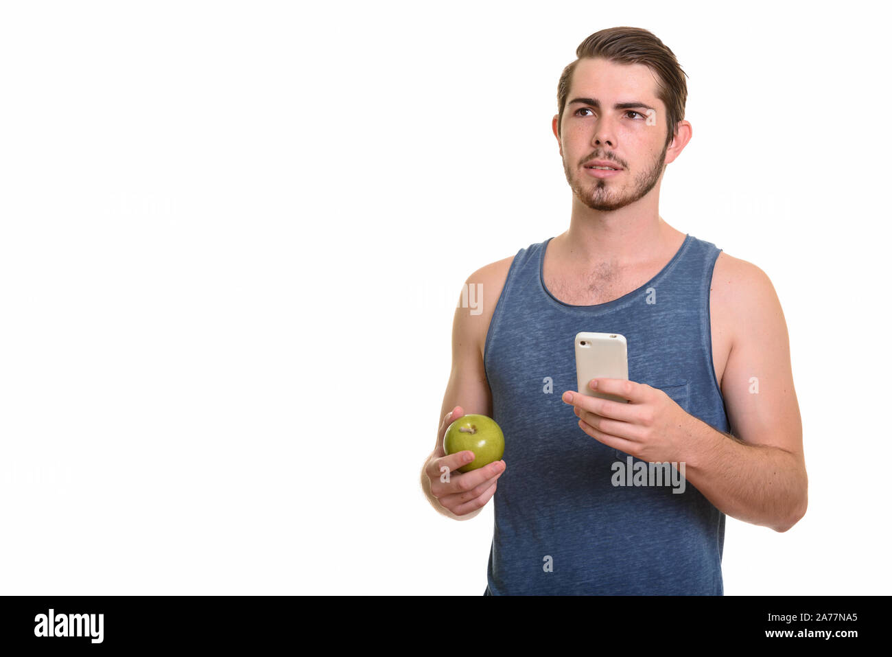 Beau jeune homme barbu holding apple et à l'aide de sport prêt pour téléphone Banque D'Images