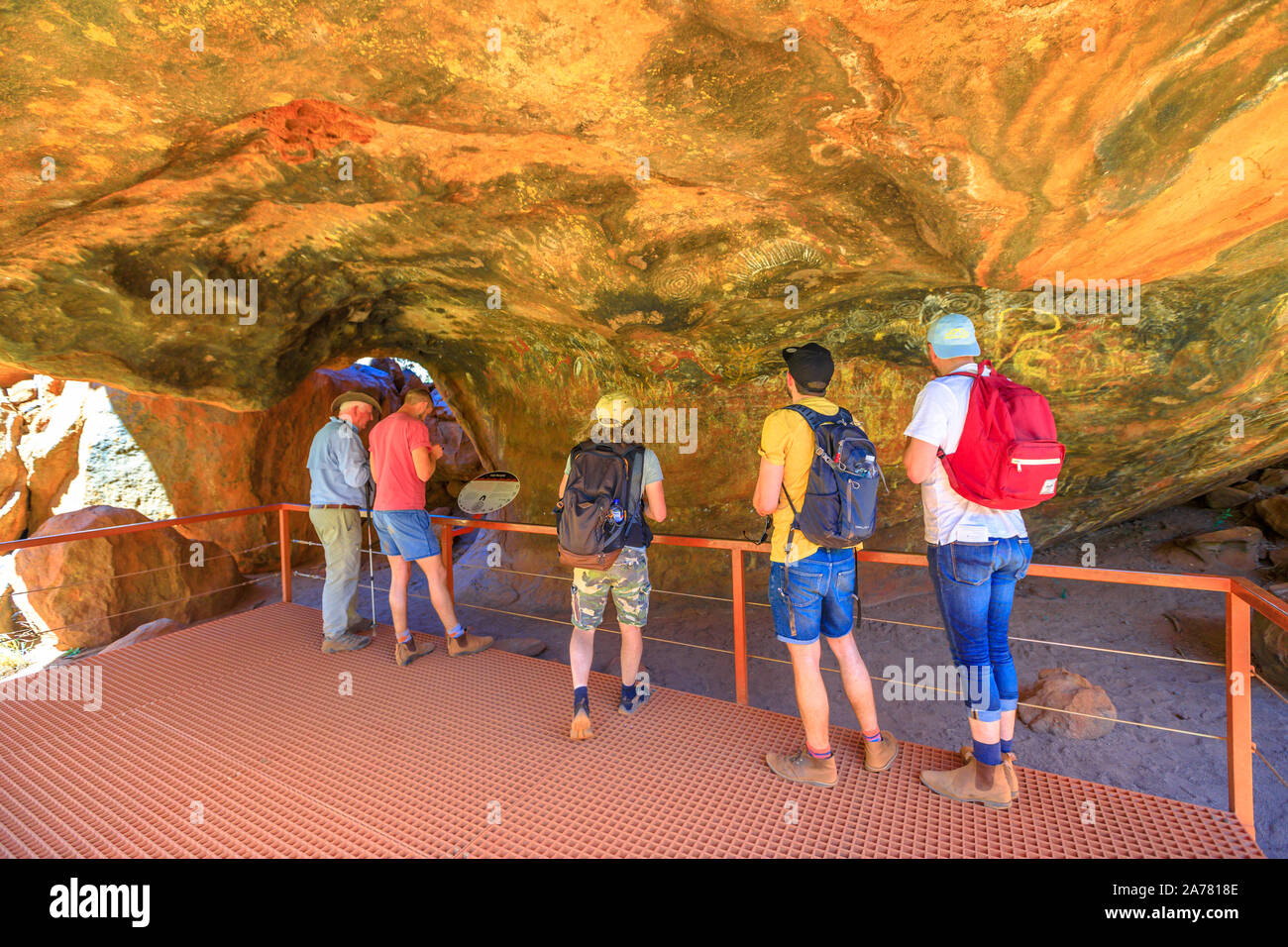 Uluru, dans le Territoire du Nord, Australie - Aug 24, 2019 : les touristes à la recherche de dessins peints sur le rocher en grotte Mutitjulu Kuniya walk ou Kulpi le long Mutitjulu Banque D'Images
