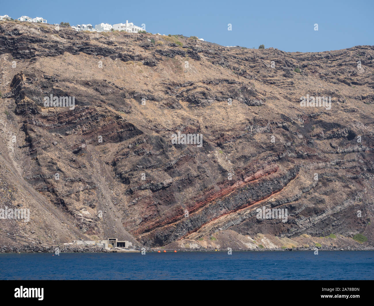 Une vue de l'eau de mer d'une coupe géologique rouge larme à Santorin fissure falaise de lave Banque D'Images