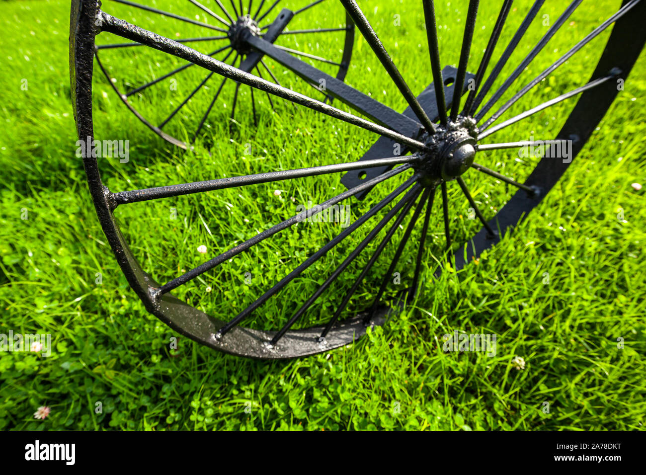 Black metal Vintage sur l'axe de roue est sur l'herbe verte au jour d'été ensoleillé. La photo en gros plan avec selective focus Banque D'Images