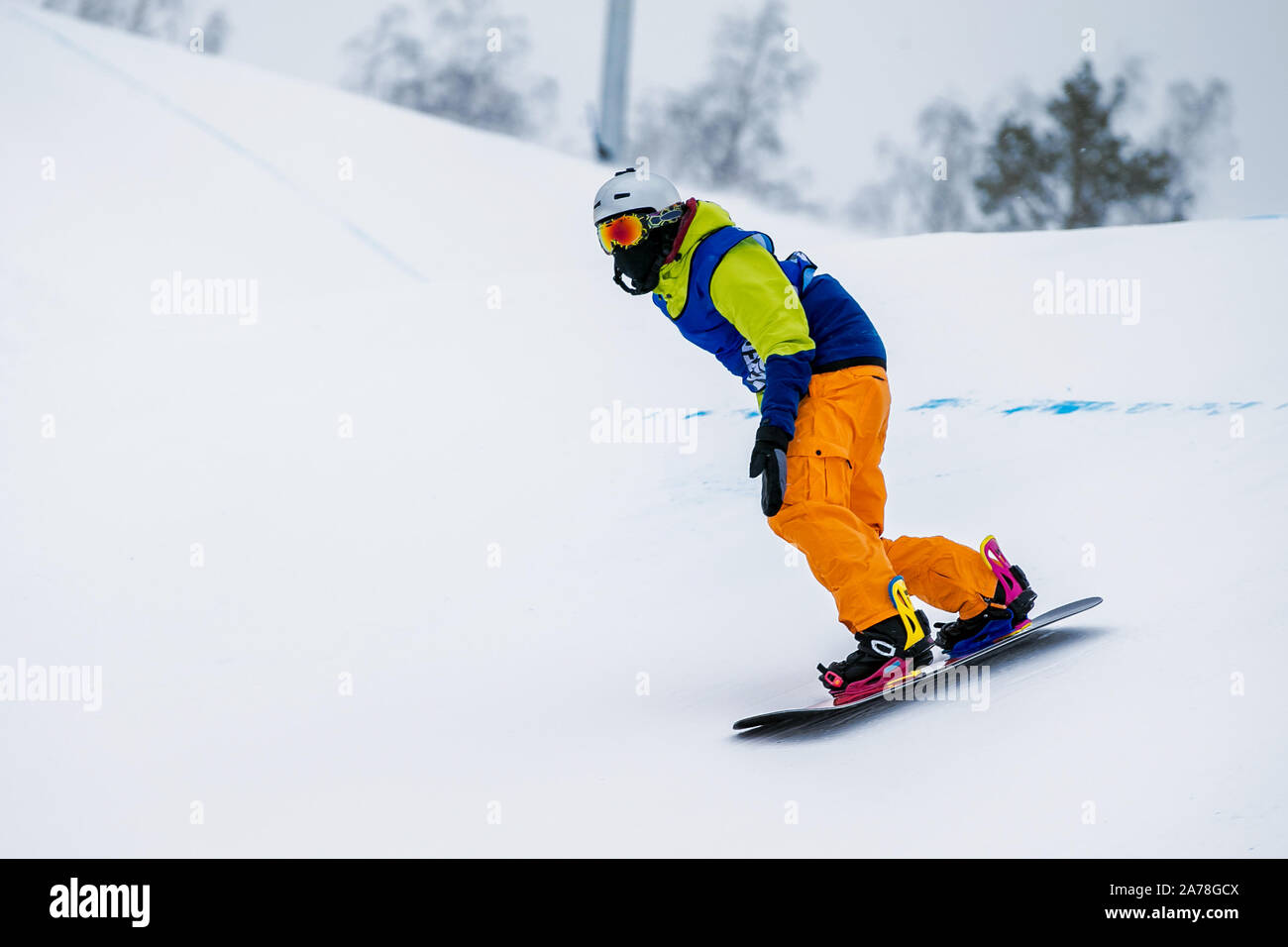 Snowboarder mâle descendant une pente couverte de neige Banque D'Images