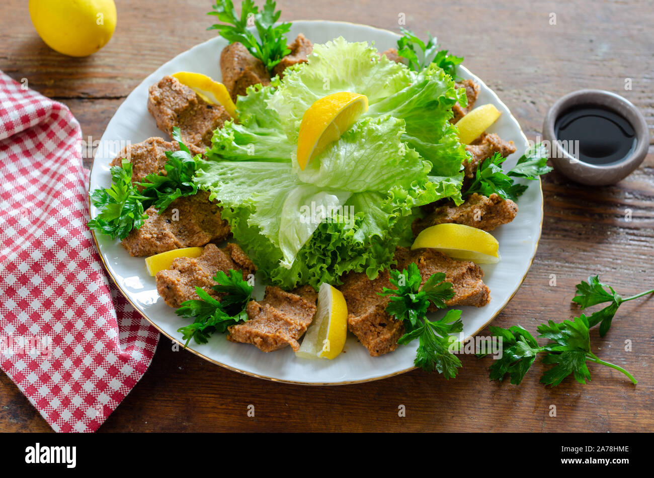 La nourriture turque : Cig Kofte avec le citron, l'assaisonnement, la laitue et le persil. Banque D'Images