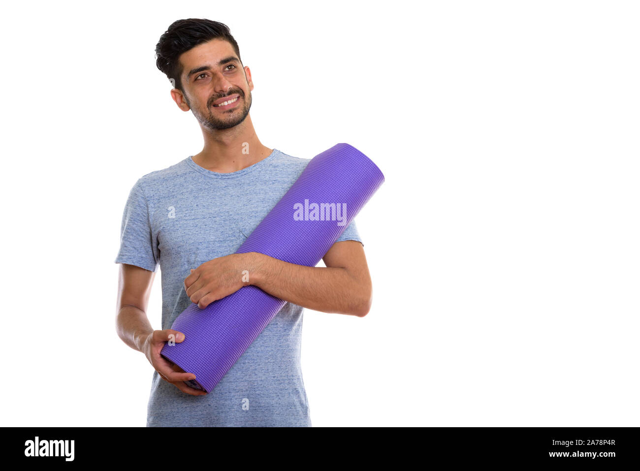 Studio shot of young man smiling persan heureux tout en maintenant un tapis de yoga Banque D'Images