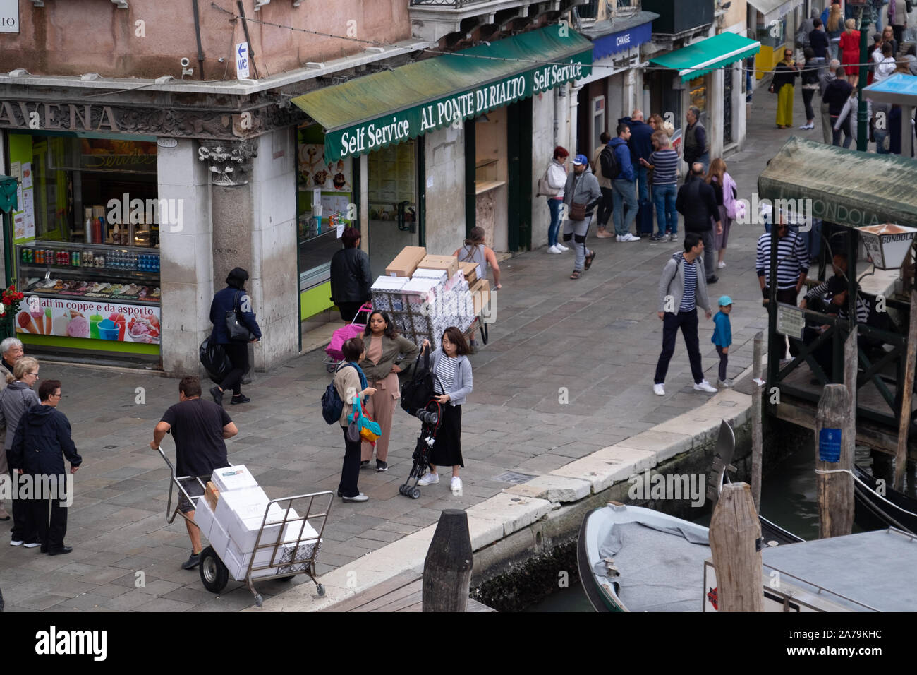 Les livraisons sont faites par les hommes en tirant ou poussant des charrettes à bras dans les rues et les ponts de Venise, au milieu des centaines de touristes. Banque D'Images