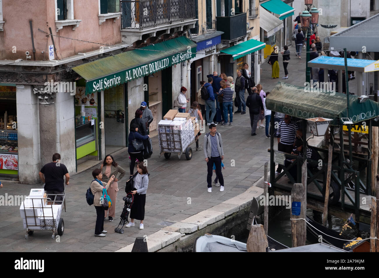 Les livraisons sont faites par les hommes en tirant ou poussant des charrettes à bras dans les rues et les ponts de Venise, au milieu des centaines de touristes. Banque D'Images