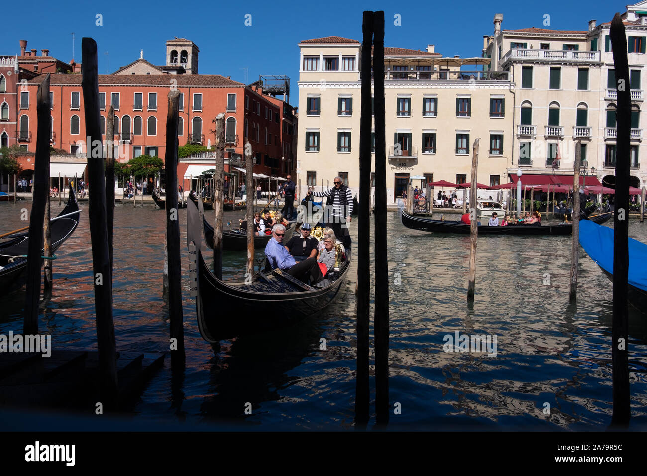 En gondole et gondolier les passagers de retour à son point d'amarrage sur le grand canal, Venise avec toile de soleil lumineux Banque D'Images