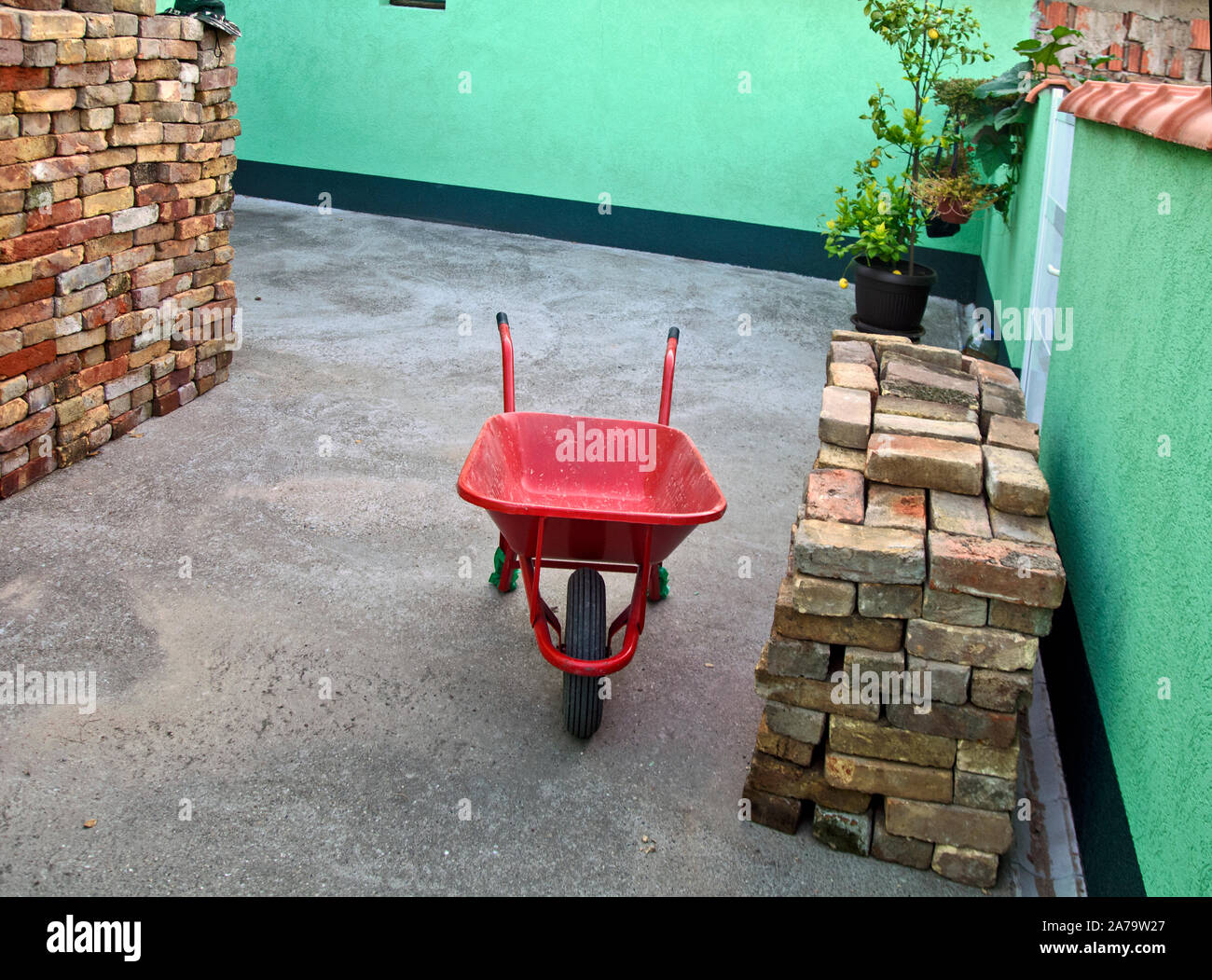 Cour avec de vieilles briques empilées et red trolley pour le transport. Seuls les maçons sont en attente pour commencer la maçonnerie. Banque D'Images