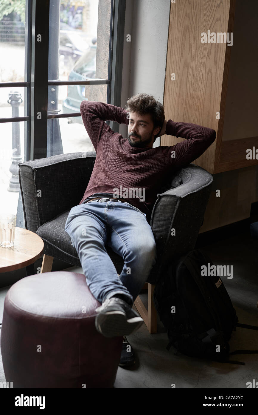 Beau jeune homme d'affaires est au repos dans un café. Beau barbu est assis à la table de cafétéria et de rêver. Banque D'Images