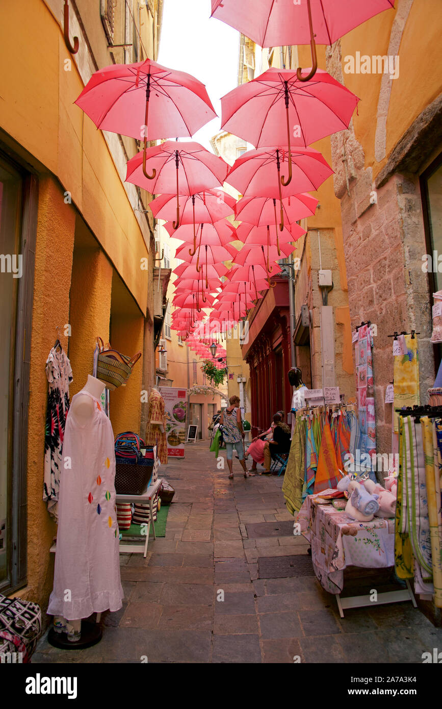 Ruelle étroite avec boutiques de vêtements et parasols roses Grasse Provence France Banque D'Images