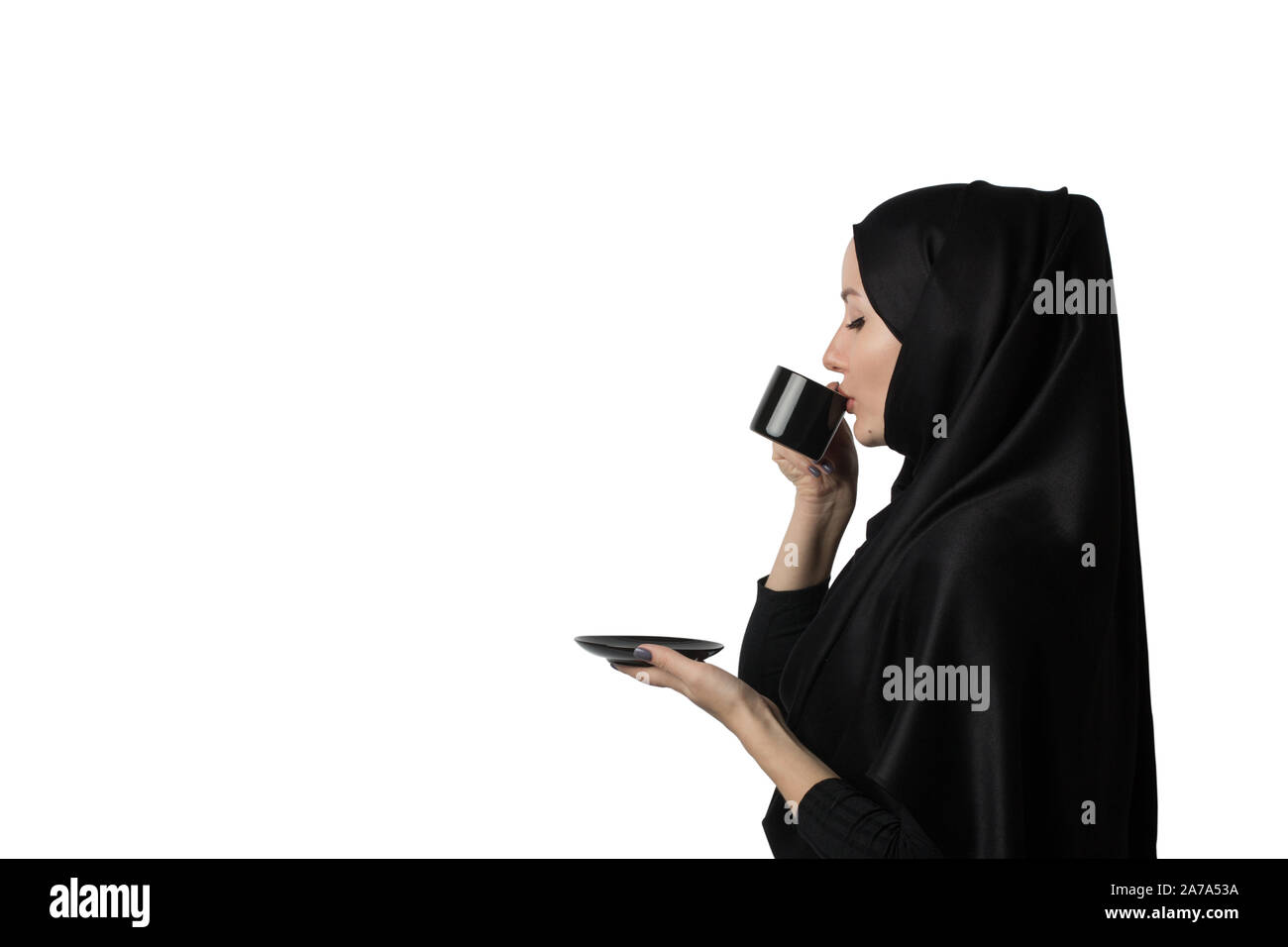 Belle femme musulmane en noir hijab avec plaisir boit du café ou thé sur fond blanc, d'isoler. Concept, modèle ou immersive pour des publicités, Banque D'Images