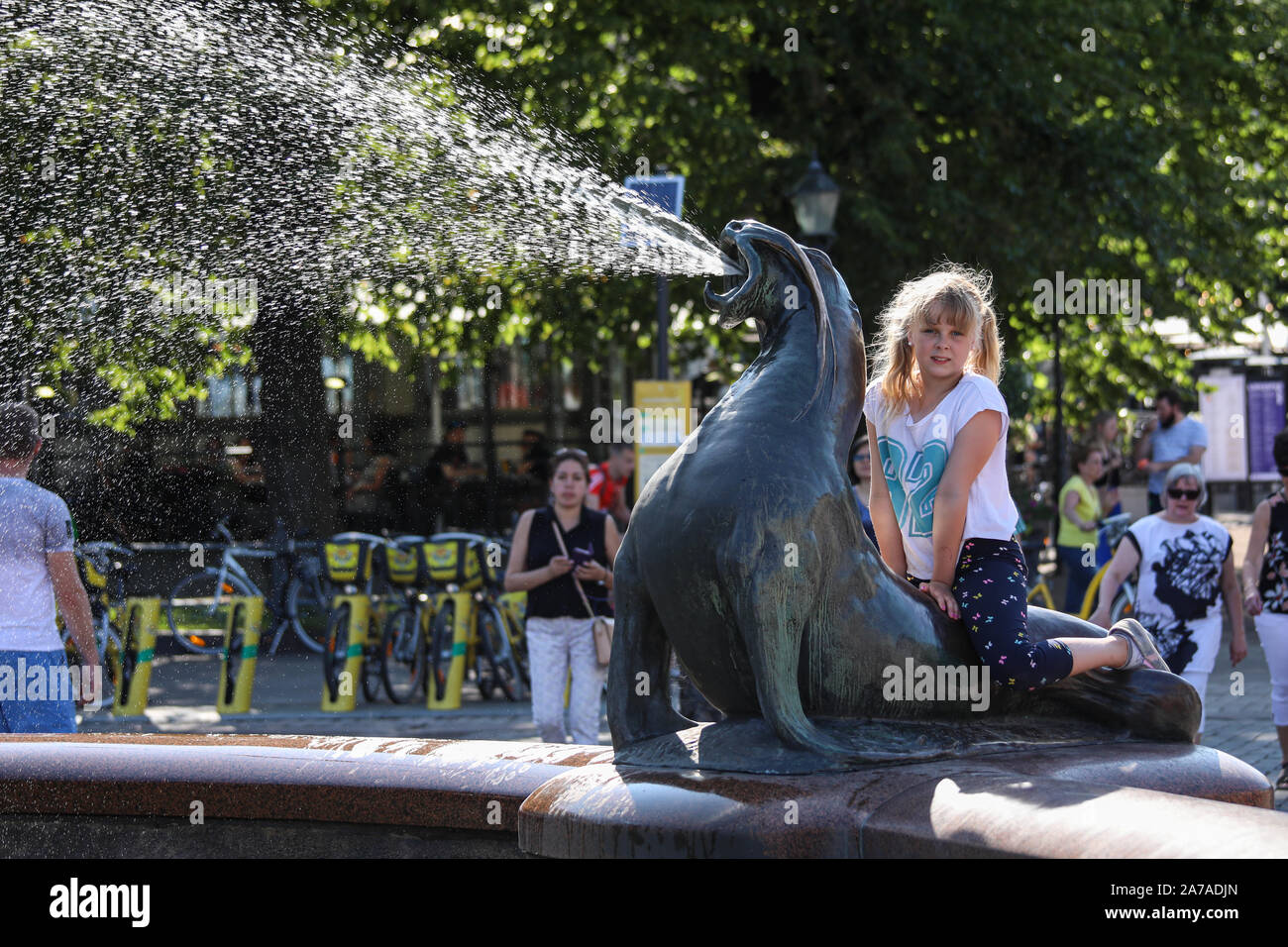Jeune fille assise sur un jet d'eau de mer lion statue Havis Amanda à Helsinki, Finlande Banque D'Images