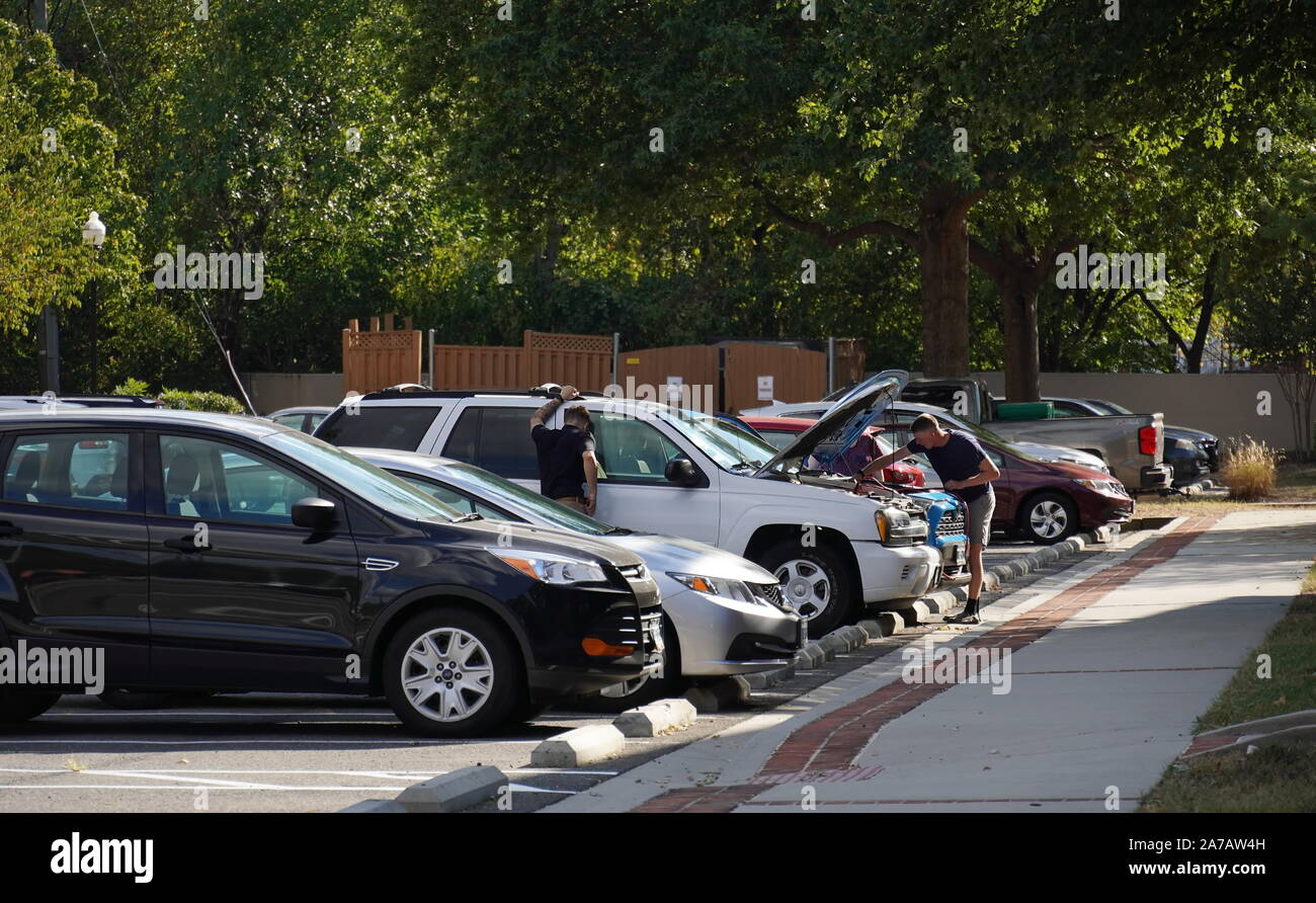 Alexandria, VA / USA - 24 septembre 2019 : Deux hommes de race blanche fixer une voiture au milieu d'un parc de stationnement résidentiel Banque D'Images