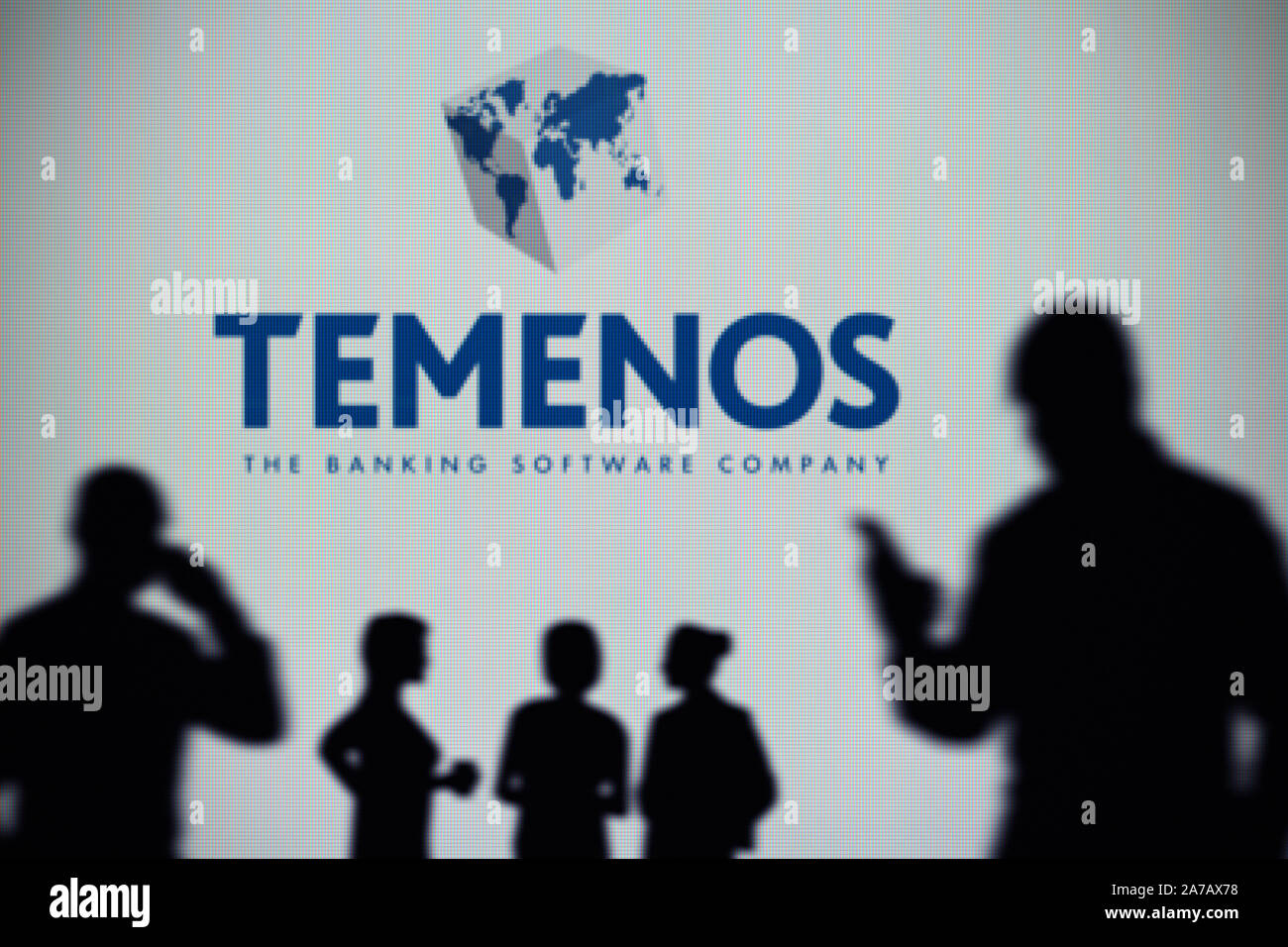 Le Groupe Temenos logo est vu sur un écran LED à l'arrière-plan tandis qu'une silhouette personne utilise un smartphone (usage éditorial uniquement) Banque D'Images