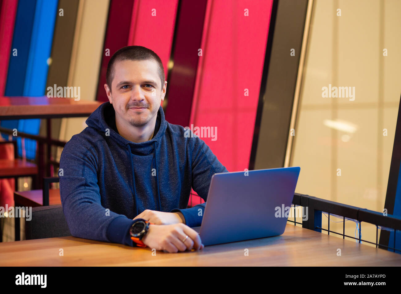 Man in hoodie with laptop sitting at desk Banque D'Images