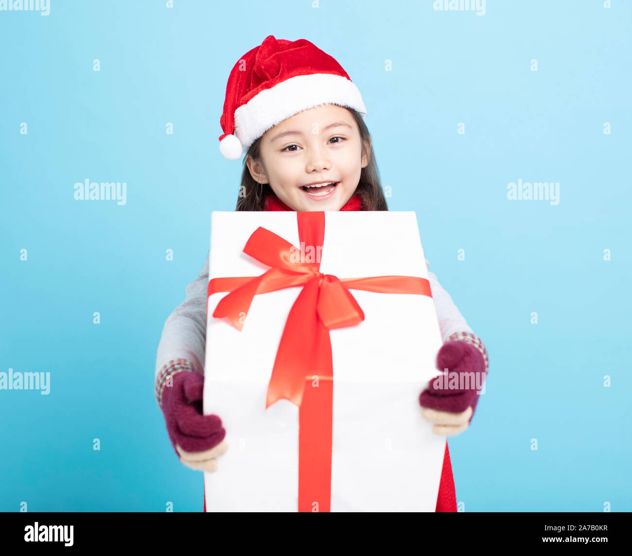 Happy little girl in Santa hat and holding gift box Banque D'Images