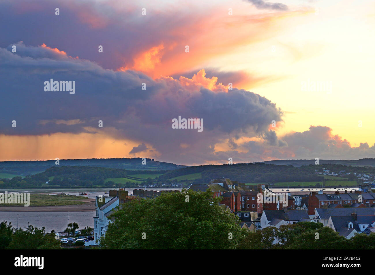 Les Cumulonimbus formée au-dessus de l'estuaire de la rivière Exe sur le coucher du soleil. Une jupe de pluie qui tombe sur les collines au loin. Une lumière dorée à l'intérieur du nuage Banque D'Images