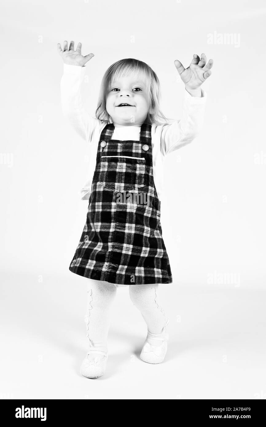 Petite blonde bébé fille avec de grands yeux bleus en robe rouge assise sur le sol, fond blanc. Portrait isolé Banque D'Images