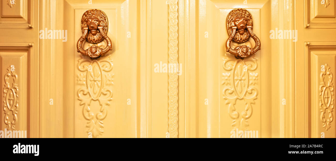 Tête de lion d'or deux heurtoirs de porte sur la porte d'ornement, l'entrée d'une villa de luxe à la maison. Banque D'Images