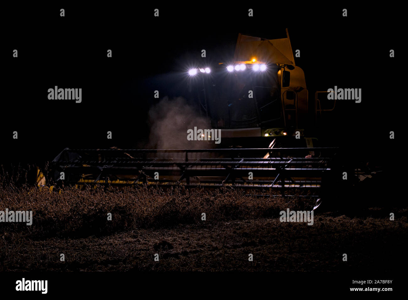 La récolteuse est présent dans le domaine de la soirée. Le blé récolté à nuit Banque D'Images